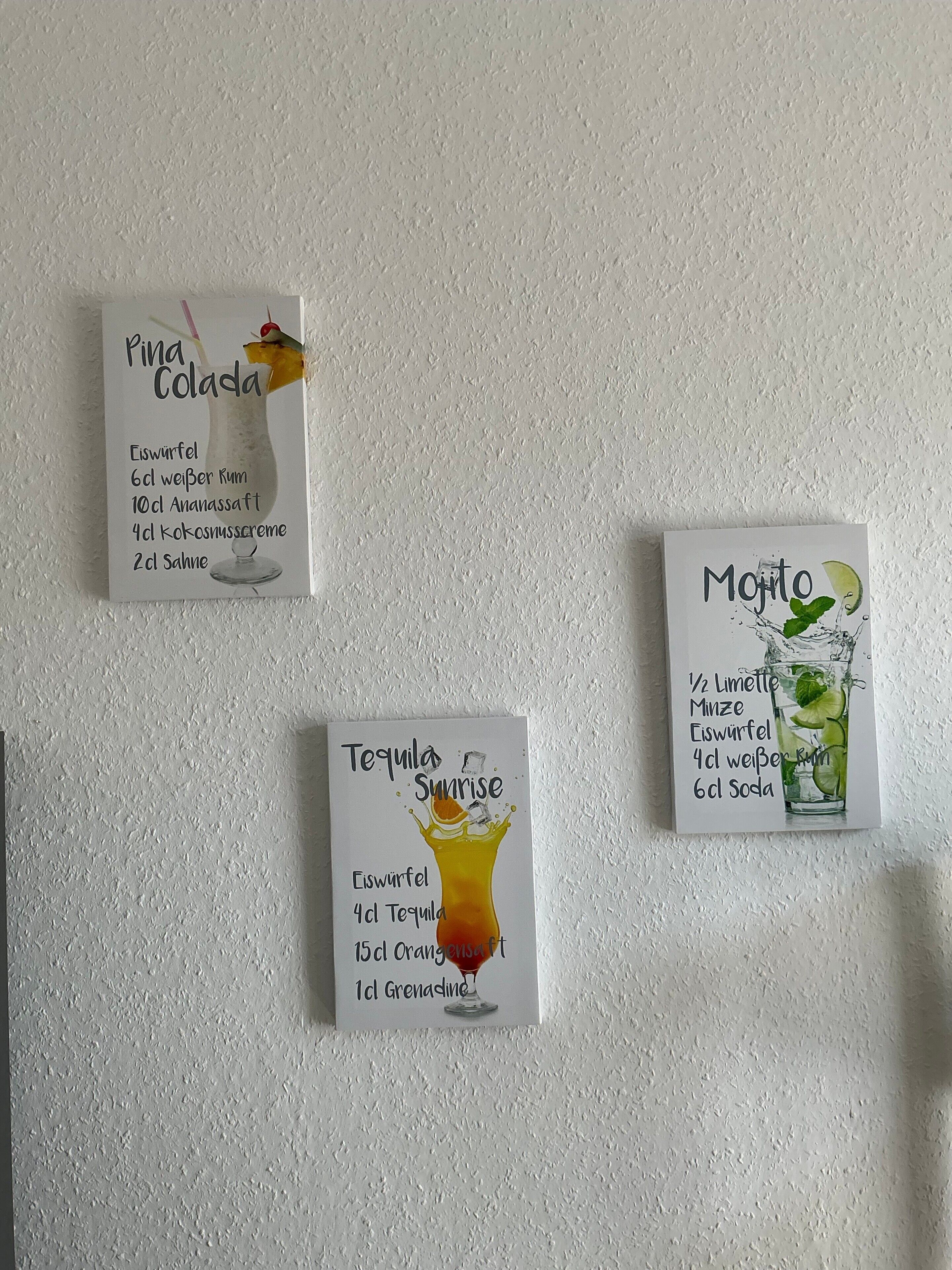 Drei Cocktail-Rezeptkarten an einer strukturierten Wand.