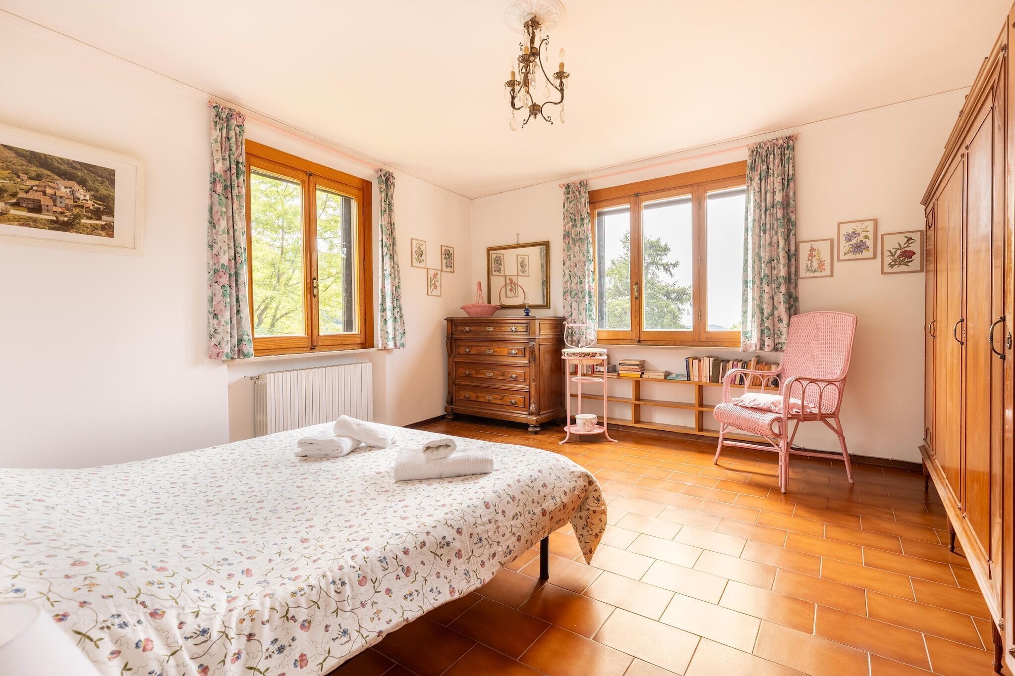 Une chambre à coucher avec un lit, une commode, une chaise et des fenêtres.