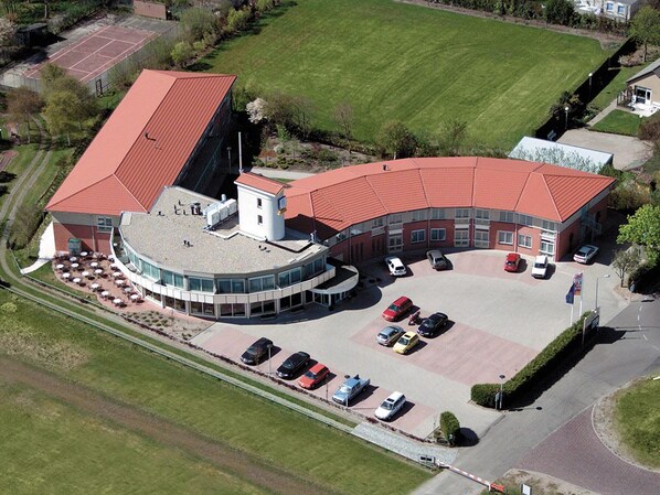 Surrounded by lush lawns and a tennis court, this building offers a tranquil retreat with a unique red roof.
