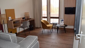 Relax in a cozy space with a comfortable sofa, desk, and TV.