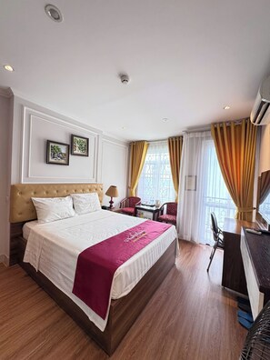 Een hotelkamer met een groot bed, een bureau, een stoel en een raam met gordijnen.