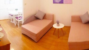 A modern living room with a sofa, a smaller couch, a round table with a plant, and a dining area with a white table and chairs. - Apartments & Rooms Cakelic II (Zupa dubrovacka)