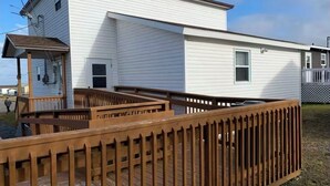 A two-story mobile home with a wooden deck and a small attached garage. - Nan’s Place Vacation Home! Traditional salt box home w/ accessibility ramp (Grand Bank)