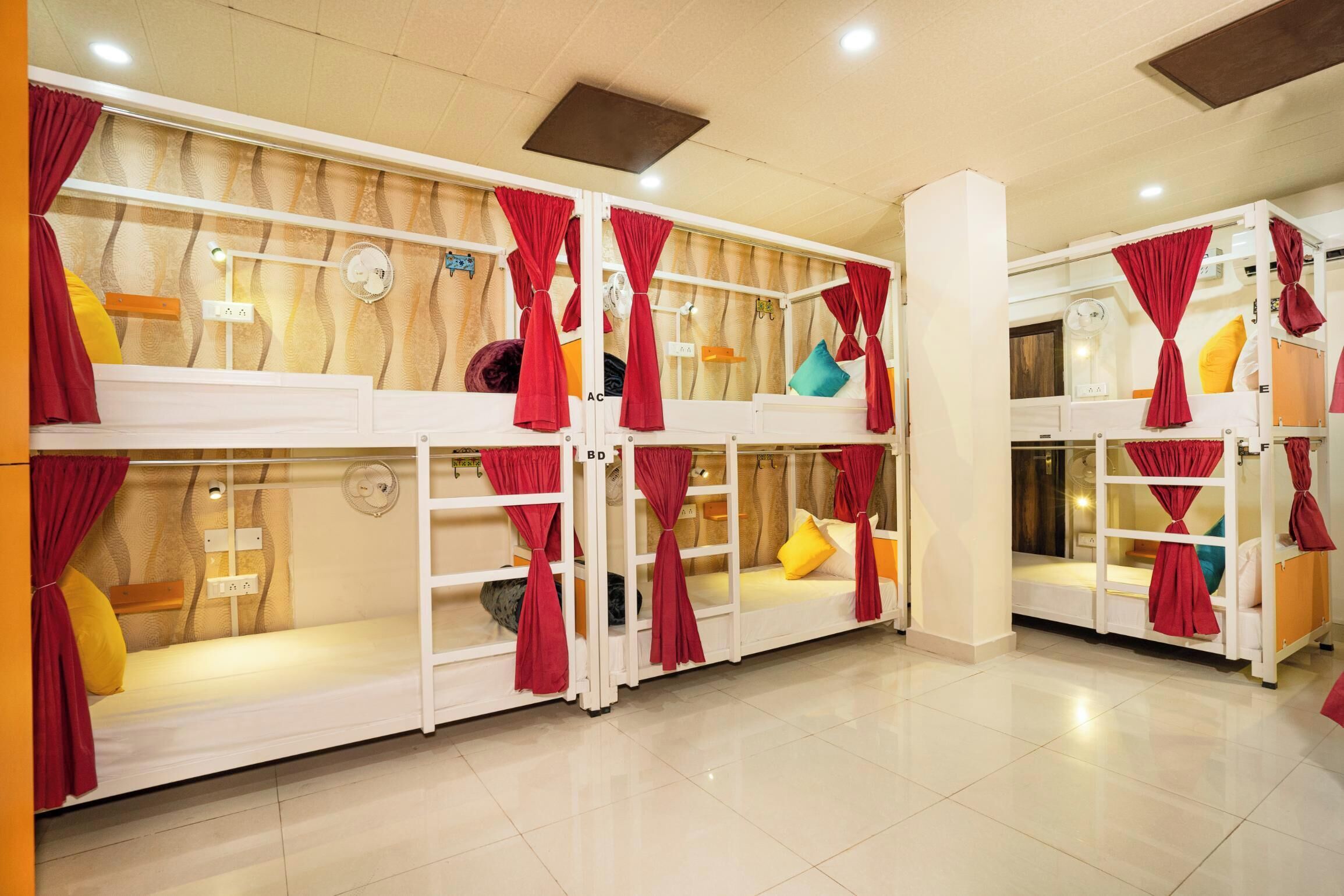 A hotel room with bunk beds, red curtains, and a tiled floor.