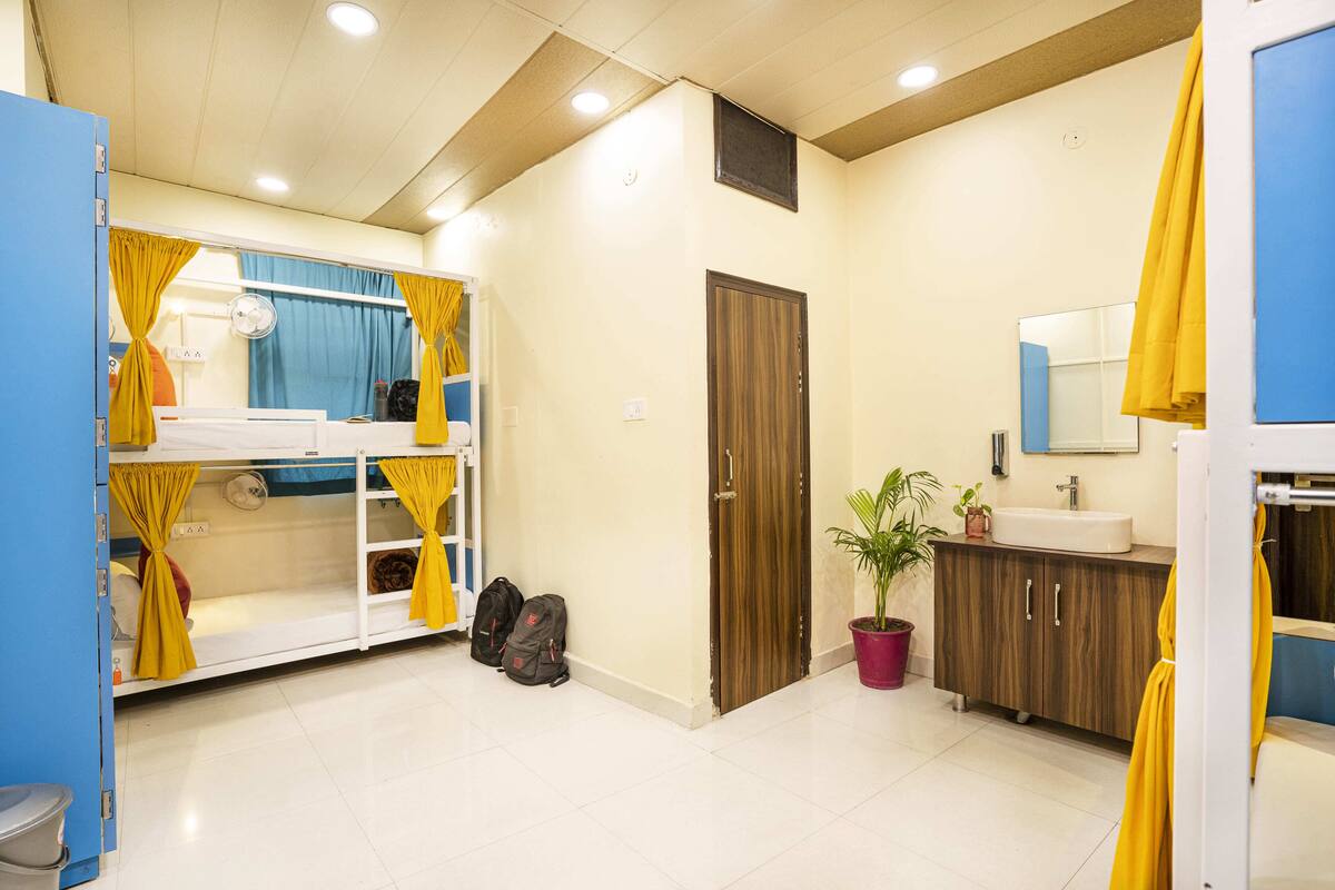 A hotel bathroom with a white sink, wooden vanity, and a shower area with yellow curtains.