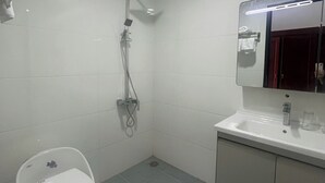 Een moderne badkamer met douche, toilet en wastafel.