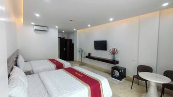 A hotel room with two beds, a TV, a small table, and a chair.