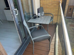 A balcony with a table and two chairs, a bottle of wine, and a glass on the table. - Stunning modern home in Lincoln (Lincolnshire)