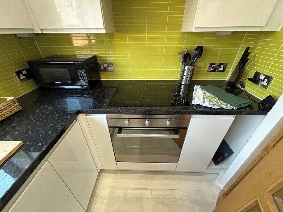 A kitchen with a microwave, oven, and various utensils on the counter.