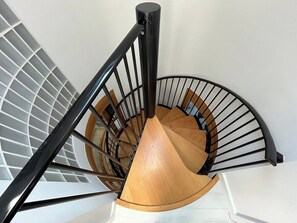 A spiral staircase with a wooden handrail and black metal balusters. - Stunning modern home in Lincoln (Lincolnshire)