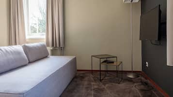 Relax in a serene space with a light grey sofa, floor lamp, and glass-topped table.
