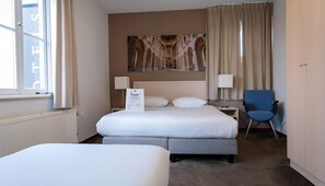 Relax in this inviting room with a large bed, a smaller bed, and a comfortable chair.