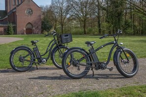 Bicycles parked on a quiet path, surrounded by trees and a brick building.