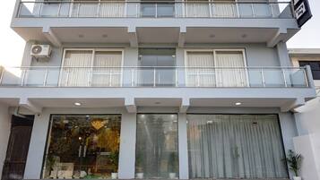 A multi-story hotel with a modern design, featuring balconies on each floor, large windows, and a prominent entrance with steps.