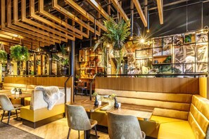 Relax in a cozy space with cushioned seating, lush greenery, and artwork on display.
