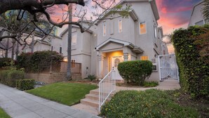 A two-story house with a front porch, a gated driveway, and a well-maintained lawn.