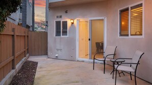 A patio area with a wooden fence, a concrete floor, and two chairs.
