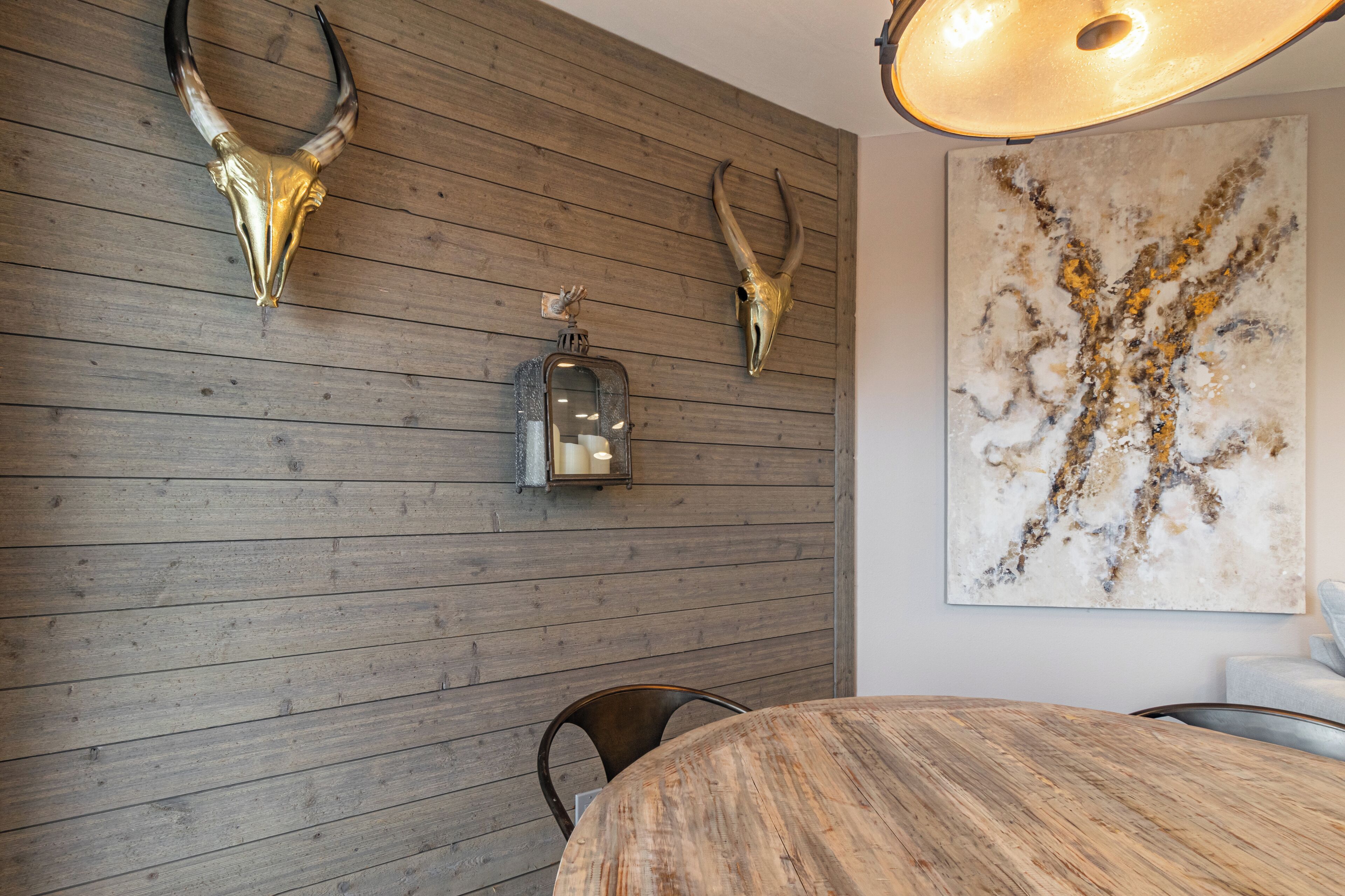 A dining area with a wooden table, chairs, and a wall-mounted light fixture.