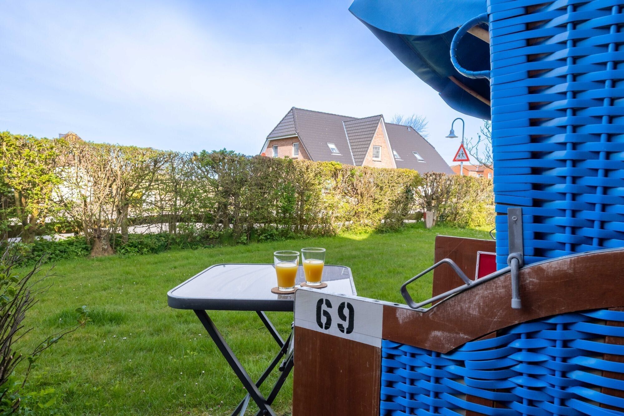 Ein Tisch mit zwei Gläsern Orangensaft, einem Schild mit der Aufschrift 69 und einem blauen Stuhl mit Webstuhl-Rückenlehne.