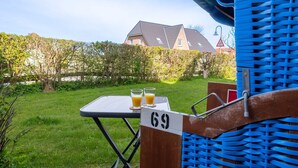 A table with two glasses of orange juice, a number 69 sign, and a blue chair with a woven backrest.