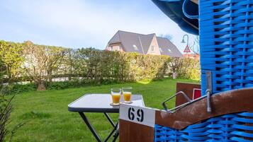 Ein Tisch mit zwei Gläsern Orangensaft, einem Schild mit der Aufschrift 69 und einem blauen Stuhl mit Webstuhl-Rückenlehne.