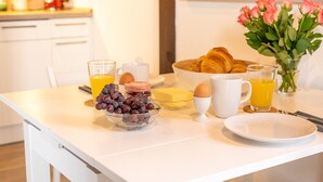 A breakfast setup with croissants, eggs, and a bowl of grapes on a white table.