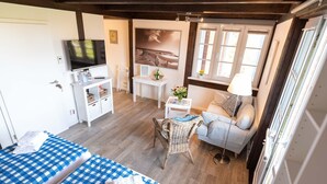 A cozy room with a bed, a sofa, a television, a small table, and a window.