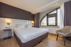 Relax in a spacious room with a large bed, bedside tables, and a comfortable chair by the window.