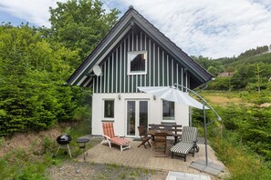 Une maison à deux étages dotée d’un balcon, d’un barbecue et de mobilier d’extérieur.