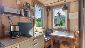 A wooden cabin interior with a kitchen area, a dining table, and a bench. - Holiday Home 'Ferienhaus Alpenzauber' with Mountain View, Private Terrace and Wi-Fi (Lennestadt)