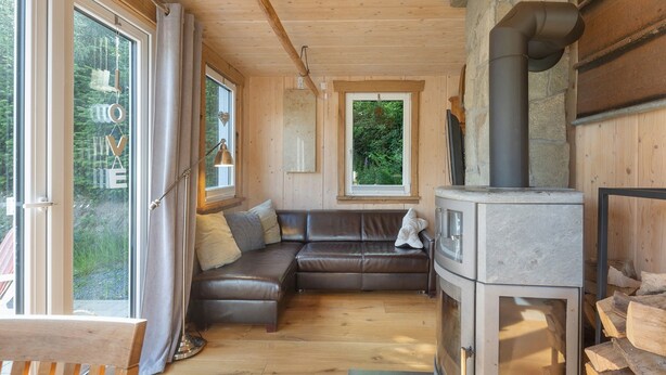 A cozy cabin interior with a wooden floor, a leather sofa, a fireplace, and large windows. - Holiday Home 'Ferienhaus Alpenzauber' with Mountain View, Private Terrace and Wi-Fi (Lennestadt)
