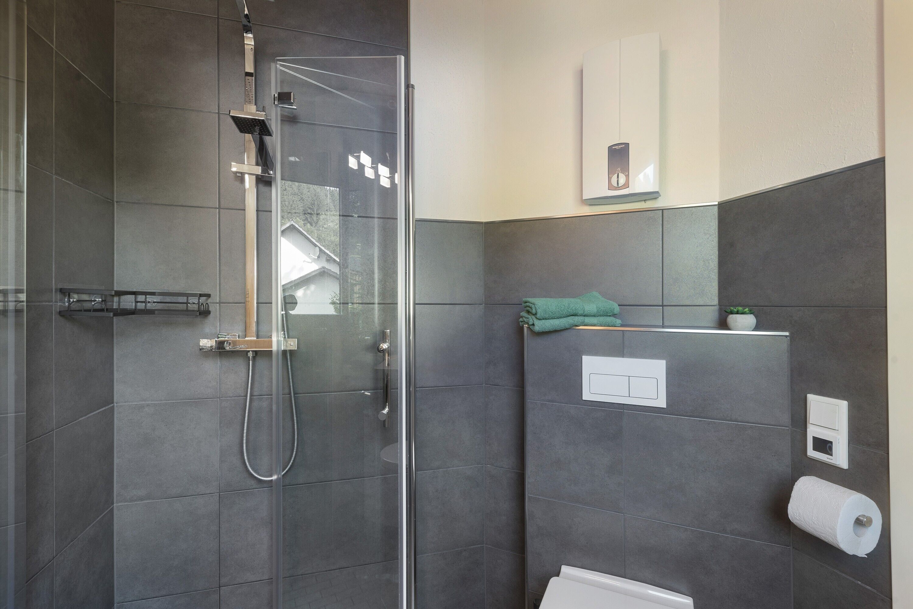 A modern bathroom with a glass-enclosed shower, a toilet, and a towel rack.