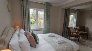A bedroom with a bed, a chair, a lamp, and a view of the outdoors. - Sparrow House (Alnwick)