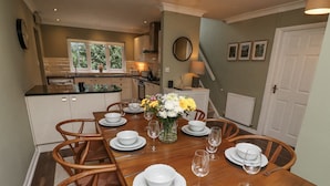 A dining area with a wooden table set for six, surrounded by wooden chairs. - Sparrow House (Alnwick)