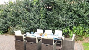An outdoor dining area with wicker furniture and a table set for four. - Sparrow House (Alnwick)