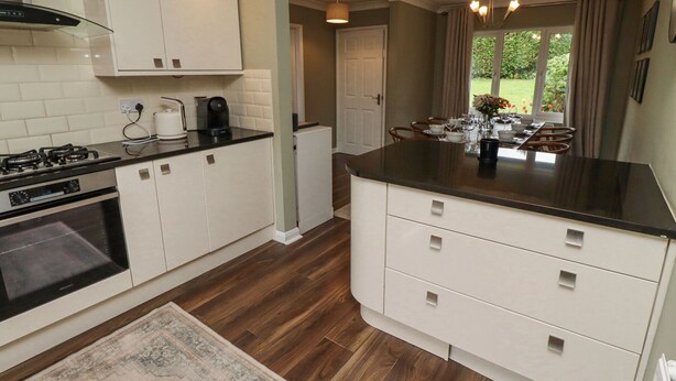 A modern kitchen with white cabinetry, a black countertop, and a built-in oven. - Sparrow House (Alnwick)