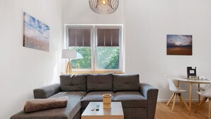 Una sala moderna con un sofá modular, una mesita, una lámpara y un comedor con sillas.