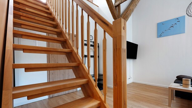 Una escalera de madera de diseño moderno, un televisor de pantalla plana montado en la pared y suelo de madera.