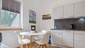 Une cuisine moderne avec des meubles blancs, un plan de travail noir et une fenêtre équipée de stores.