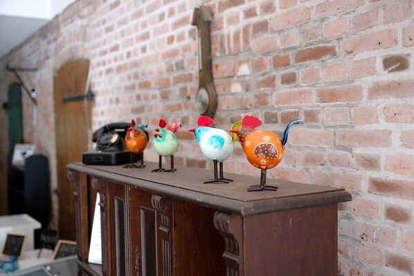 A brick wall with a wooden cabinet displaying colorful ceramic birds.