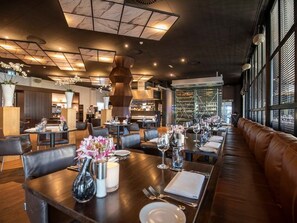 Enjoy a meal in style at this elegant dining area, featuring a long dining table, comfortable leather booths, and a wine rack.