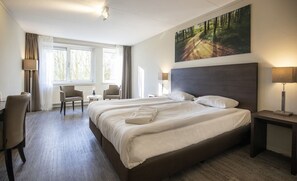 Relax in comfort with a large bed, bedside tables, and a chair, surrounded by a serene atmosphere.