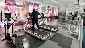 Un gimnasio con cintas de correr, elípticas y máquinas de pesas.