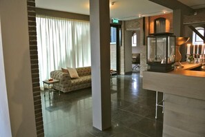 Relax in a spacious living area with a modern design, featuring a plush sofa, armchair, and contemporary fireplace.