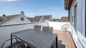 A rooftop terrace with a wooden table and chairs, a white chair, and a view of neighboring buildings. - Apartment 'Mit Dachterrasse' with Lake View, Balcony and Wi-Fi (Heide)