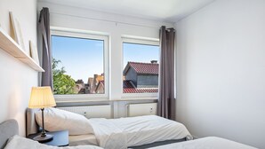 A bedroom with a bed, a nightstand, a lamp, and a window with curtains. - Apartment 'Mit Dachterrasse' with Lake View, Balcony and Wi-Fi (Heide)