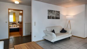 Una sala de estar moderna con un sofá blanco, una mesa de centro de madera, un cuadro en la pared y una lámpara.