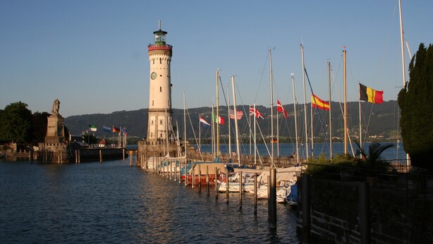 A lighthouse, a dock with boats, and flags. - Apartment '5' with Lake View, Shared Terrace and Wi-Fi (Lindau am Bodensee)