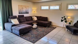 Un salon moderne avec un canapé d’angle, un tapis à motifs et une plante en pot.
