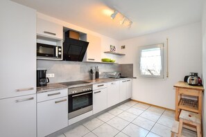 A modern kitchen with white cabinets, a built-in oven, a microwave, and a coffee maker. - Apartment '2' with Shared Terrace, Shared Garden and Wi-Fi (Lindau am Bodensee)